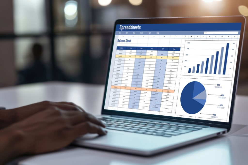Laptop screen showing a spreadsheet with a balance sheet and a bar chart, in an office setting.