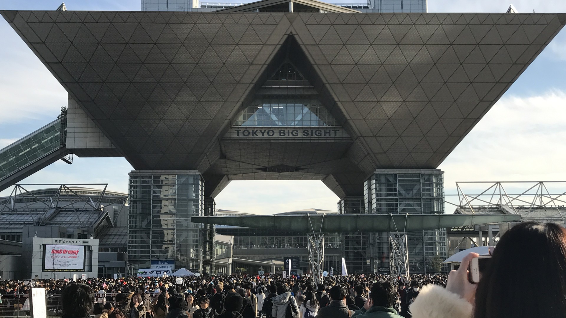 東京ビッグサイトの逆三角形の会議棟の下に、コミックマーケット91に集まった大勢の参加者の後ろ姿が広がる