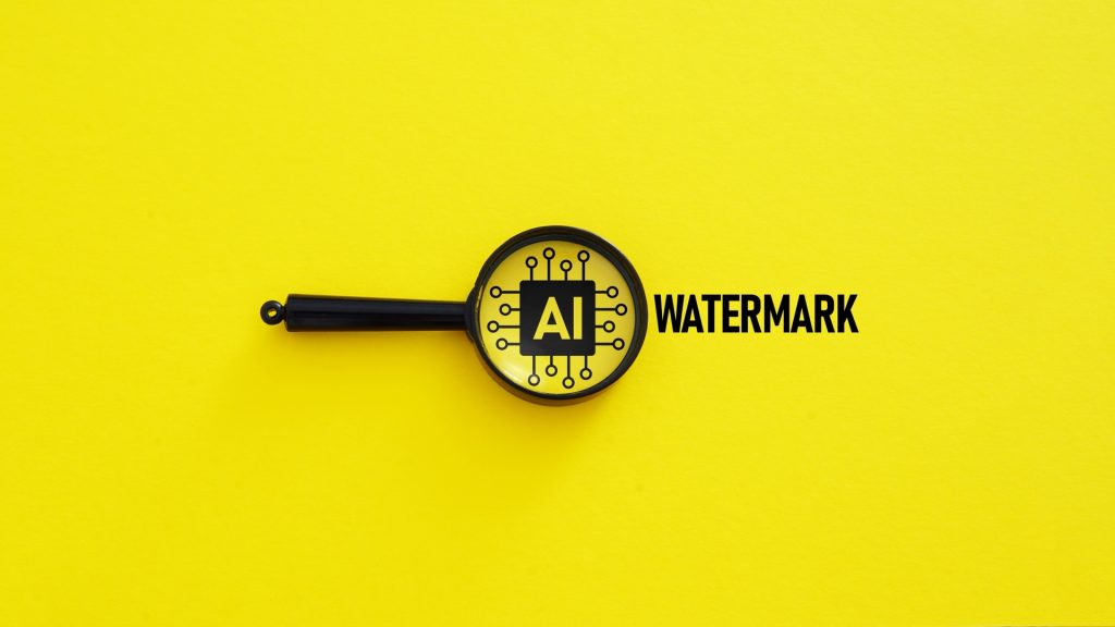 黄色の背景に置かれた虫眼鏡。レンズの中にAIの回路アイコン、隣にWATERMARKの文字